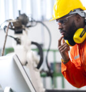 portrait-native-american-engineer-technician-wearing-safty-uniform-hand-contril-automation-robot-arm-welding-machine-with-laptop-industrial-40-factory-background-concept (FILEminimizer)